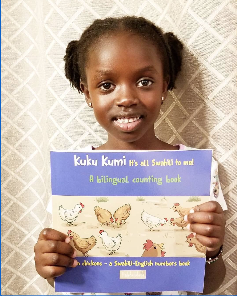 Young reader proudly holding Kuku Kumi — a bilingual Swahili-English counting book